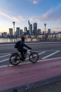 Skyline of the city centre of Frankfurt am Main, cyclist on the Ignatz-Bubis-Bridge, dusk, river