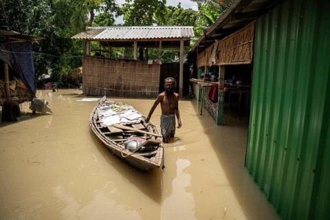 Morigaon, India. 4 July 2024. A person dry his childrens books in a boat next to his flooded house