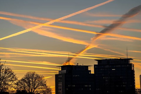 Condensation trails from aircraft flying at high altitude, evening sky, after sunset