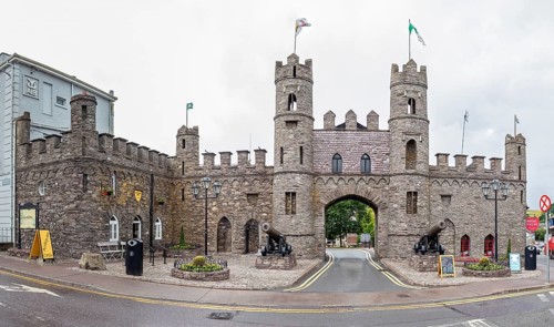 Imposing stone castle with flags and cannons, historical character on the street corner, Macroom