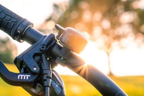 Bicycle handlebars with bell in the sunset, nature and trees in the background, forest bike,
