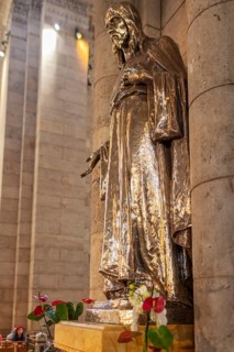 Metal statue in a church, surrounded by flowers, shown in architectural detail, Paris