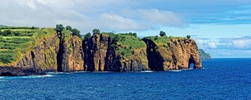 Coastal cliffs looking like a giant elephant with vegetation at the edge of the blue ocean and
