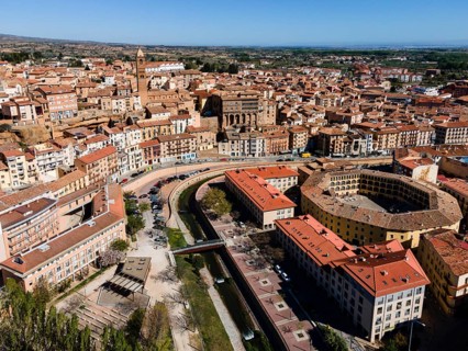 Aerial view of a historic city with tiled roofs, bridges over a river and a central square, aerial