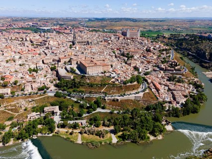 Aerial view of a historic city with a river, several bridges and prominent buildings on hills,