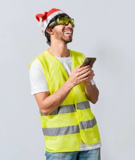 Happy Engineer in christmas hat using cell phone isolated. Smiling engineer in christmas hat using