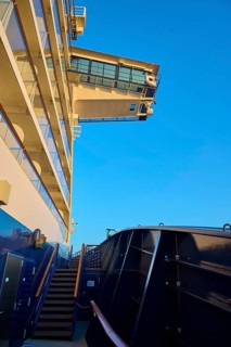 Modern cruise ship substructure with railings, windows and bridge under a bright blue sky with a