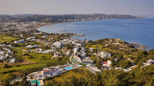 View of Faliraki, view of a coastal town with numerous buildings and blue water in the background,