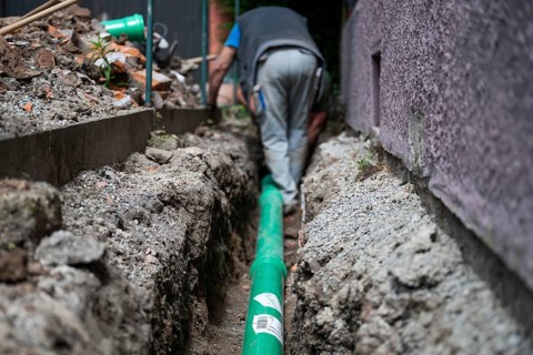 Construction worker, newly laid green sewage pipe, trench, Stuttgart, Baden-Württemberg