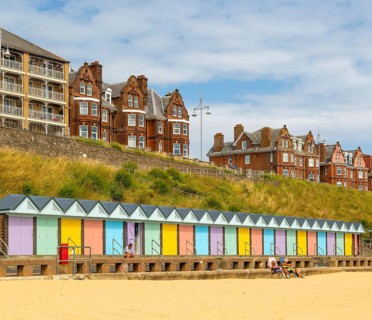 Colourful beach huts and historic clifftop buildings, South Beach, Lowestoft, Suffolk, England, UK