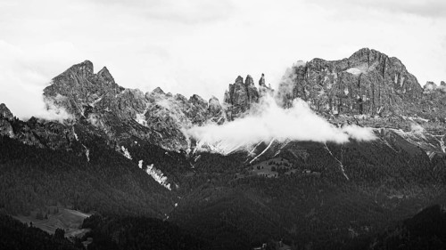 The peaks of the rose garden, shrouded in mist, drone shot, black and white image, Dolomites,