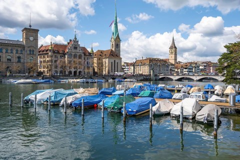 Boats at the jetty in the river Limmat, towers of Fraumünster and St Peter, Old Town, Zurich,