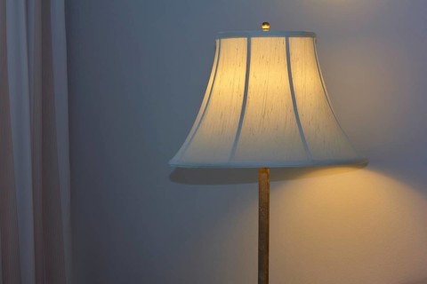 A warmly illuminated bedside lamp with a white shade, cosy