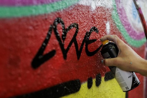 A man sprays graffiti on a wall with a spray can. Berlin, 14.08.2024