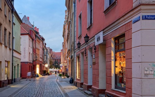 Shop windows illuminated in the evening on Szewska Street in the medieval Old Town of Thorn. The
