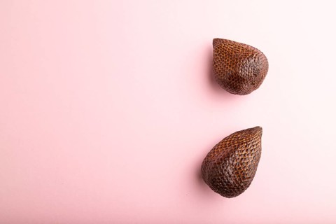Salak or snake fruit on pink pastel background. Top view, flat lay, copy space. Tropical, healthy