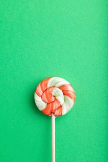 Single lollipop candy on green pastel background. copy space, top view, flat lay