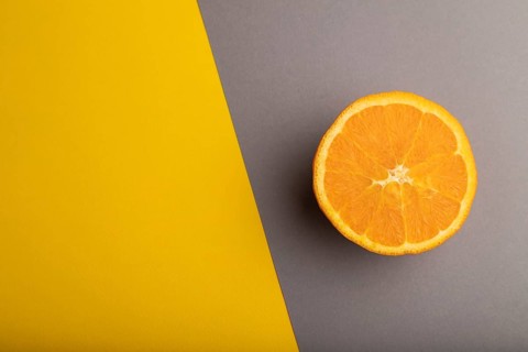 Ripe cut orange on gray and yellow pastel background. Top view, flat lay, copy space. Tropical,