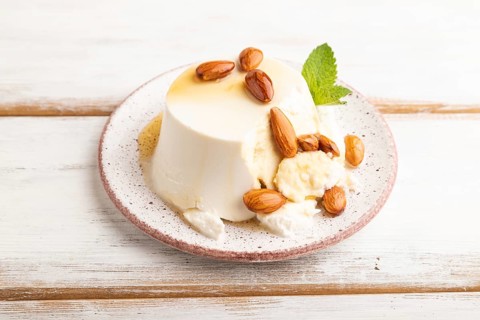 Ricotta cheese with honey and almonds on white wooden background. side view, close up