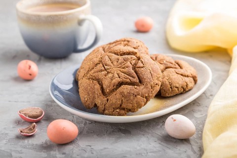 Homemade oatmeal cookies with a cup of cocoa and a yellow textile on a gray concrete background.