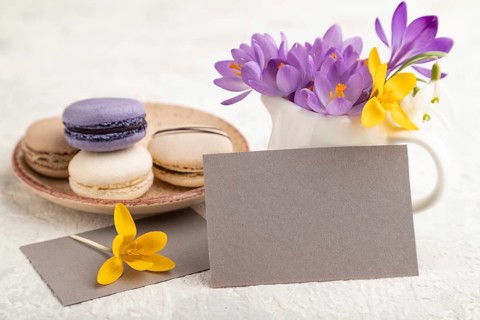 Gray paper business card mockup with spring snowdrop crocus flowers and multicolored macaroons on