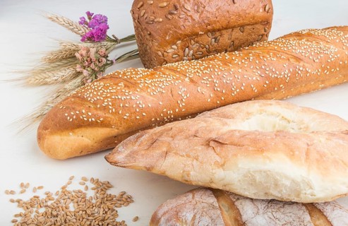 Different kinds of fresh baked bread on a white wooden background. side view, close up