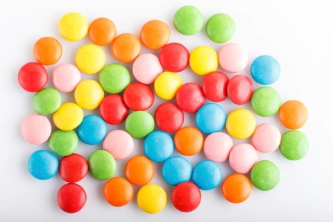 Colorful multicolored chocolate candy dragees isolated on white background. Top view, close up