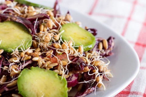 Vegetarian salad of purple cabbage, germinated wheat, tomatoes and avocado on linen tablecloth,