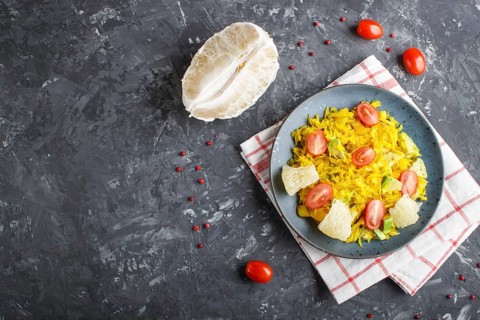 Fried pomelo with tomatoes and avocado on black concrete background. Top view, copy space, myanmar