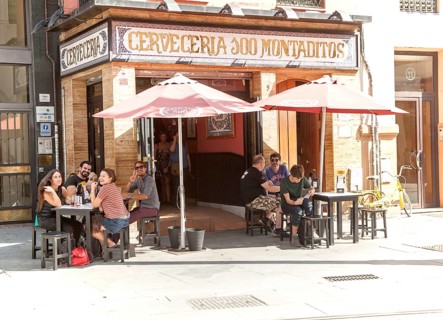 Happy people waving outside traditional cerveceria bar in central Seville, Spain, Europe