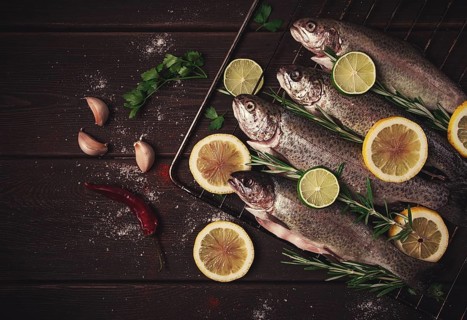 Raw rainbow trout, with lemon and herbs, on a wooden table, no people