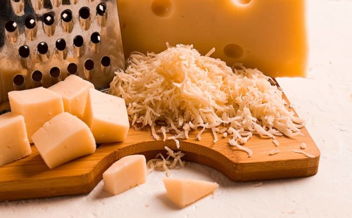 Grated cheese, Maasdam, on a cutting board, grater and cheese knife, close-up, no people