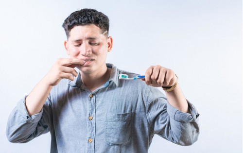 Person with gingivitis holding toothbrush isolated. Man suffering from gum pain holding toothbrush.