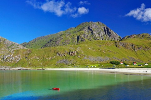 Crystal clear sandy beach with turquoise green water and a green boat, Haukland Strand, Leknes,