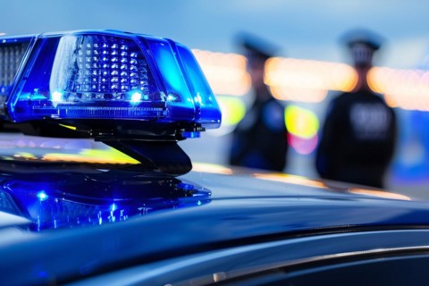 Close up of blue police car light with two police men in blurry background. KI generiert,