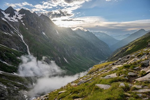 Atmospheric mountain landscape, clouds forming in a mountain valley in the evening light,
