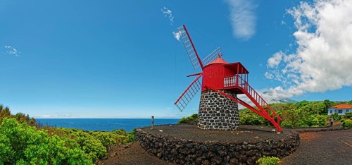 Red painted windmill on black volcanic stone Moinho de São João under a wide sky, São João, Pico