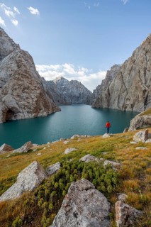 Tourist at the blue mountain lake between rocky steep mountain peaks, Kol Suu Lake, Sary Beles