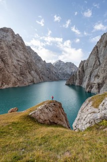 Tourist at the blue mountain lake between rocky steep mountain peaks, Kol Suu Lake, Sary Beles