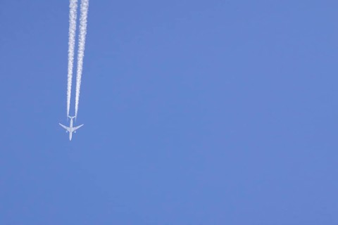 Airbus aircraft of Qatar airways flying across a blue sky with a vapour trail or contrail behind,