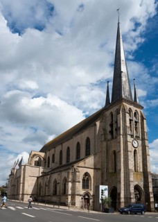 Alte Kirche mit hohem Turm unter einem teilweise bewölkten Himmel an einer Straße, Kirche, Église