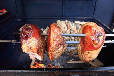 Pork knuckles are grilled on a spit over a wood fire