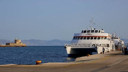 People at a harbour with ferry and old coastal fortification in the background, Fort of Saint