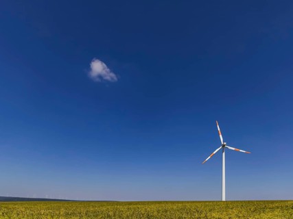 Wind turbine in an open field, a small cloud clouds the blue sky. Swabian Alb, Geislingen an der