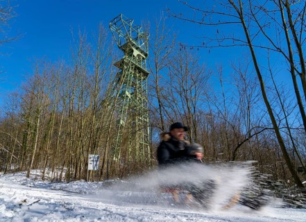 Winter in the Ruhr area, toboggan run on a forest path at Lake Baldeney, headframe of the former