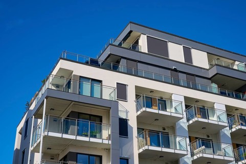 Modern residential building with several balconies and a façade under a clear blue sky, Molde,
