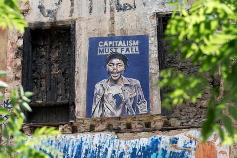 Poster critical of capitalism with a portrait of a coloured man in Exarchia, district of the