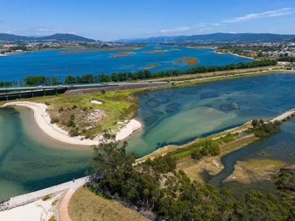 A natural area criss-crossed by rivers and islands with blue water and mountains in the background,
