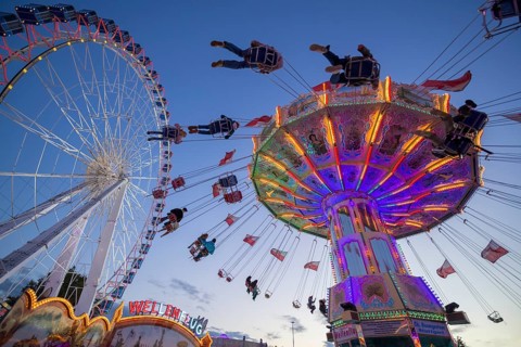 A funfair at dusk with illuminated chain carousel and Ferris wheel, Europa Rad, rides, wave flight,