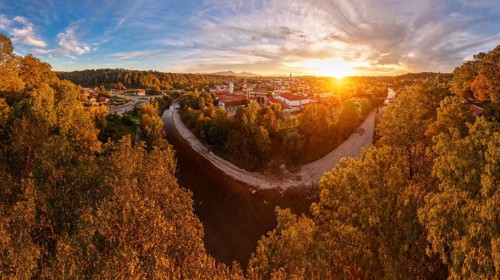 View of a town at sunset, surrounded by a river and autumnal trees under a dramatic sky, Traunstein
